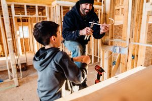 Boy and man building a house. Tradelines can help to build credit.